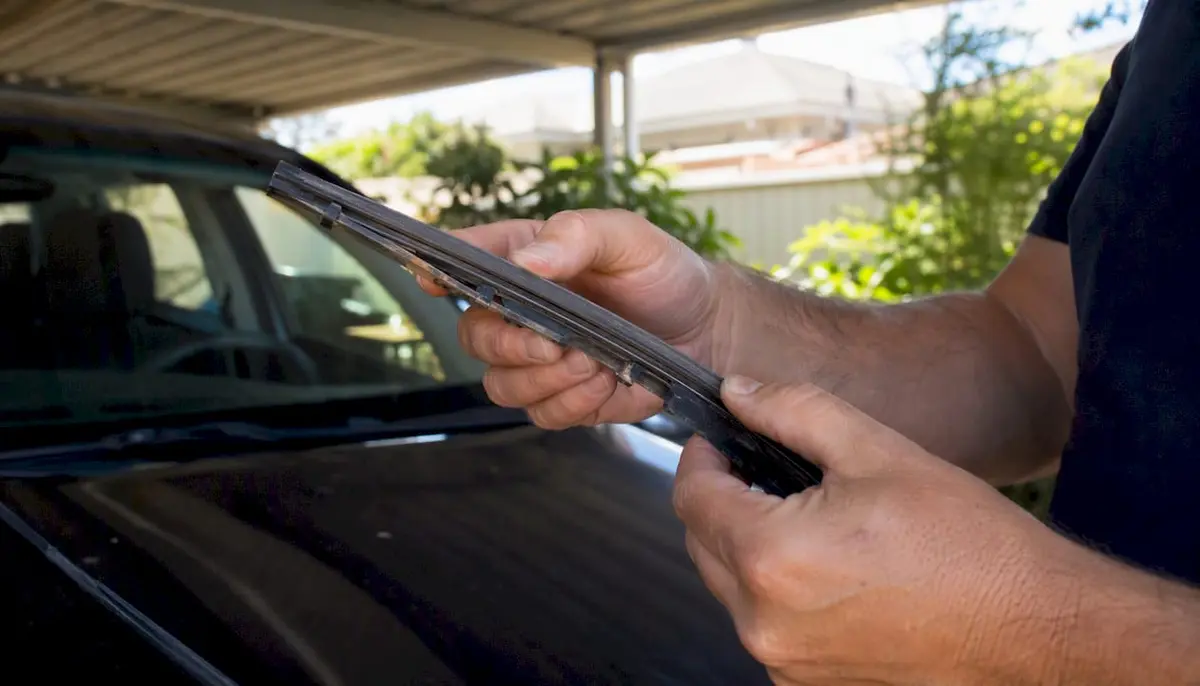 Close-up of hands checking worn wiper blade