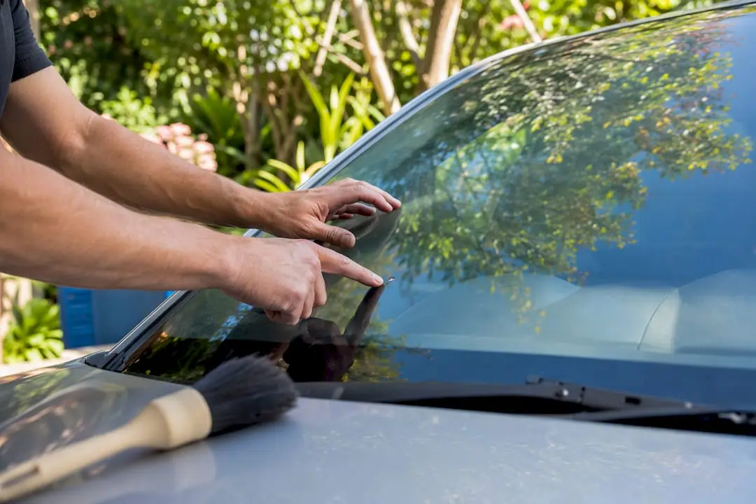 Hands inspecting stone chip on windscreen