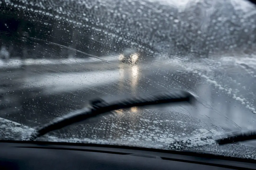 Car windshield with icy rain and wiper blades in use