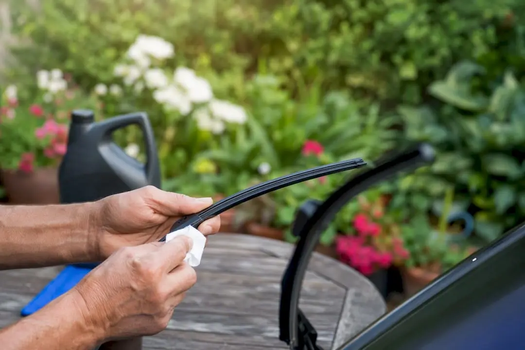 Hands cleaning a windshield wiper blade
