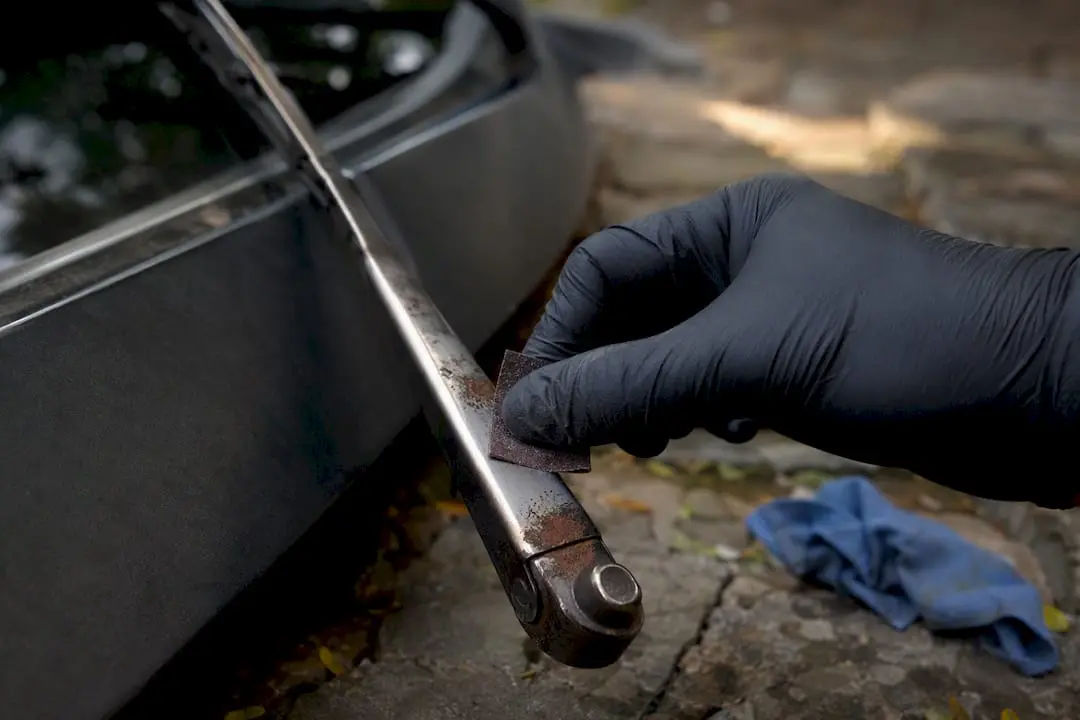 Gloved hand sanding rust off wiper arm