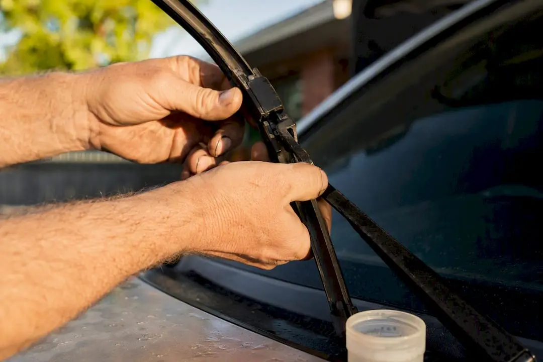 Hands removing wiper blade with oil spray