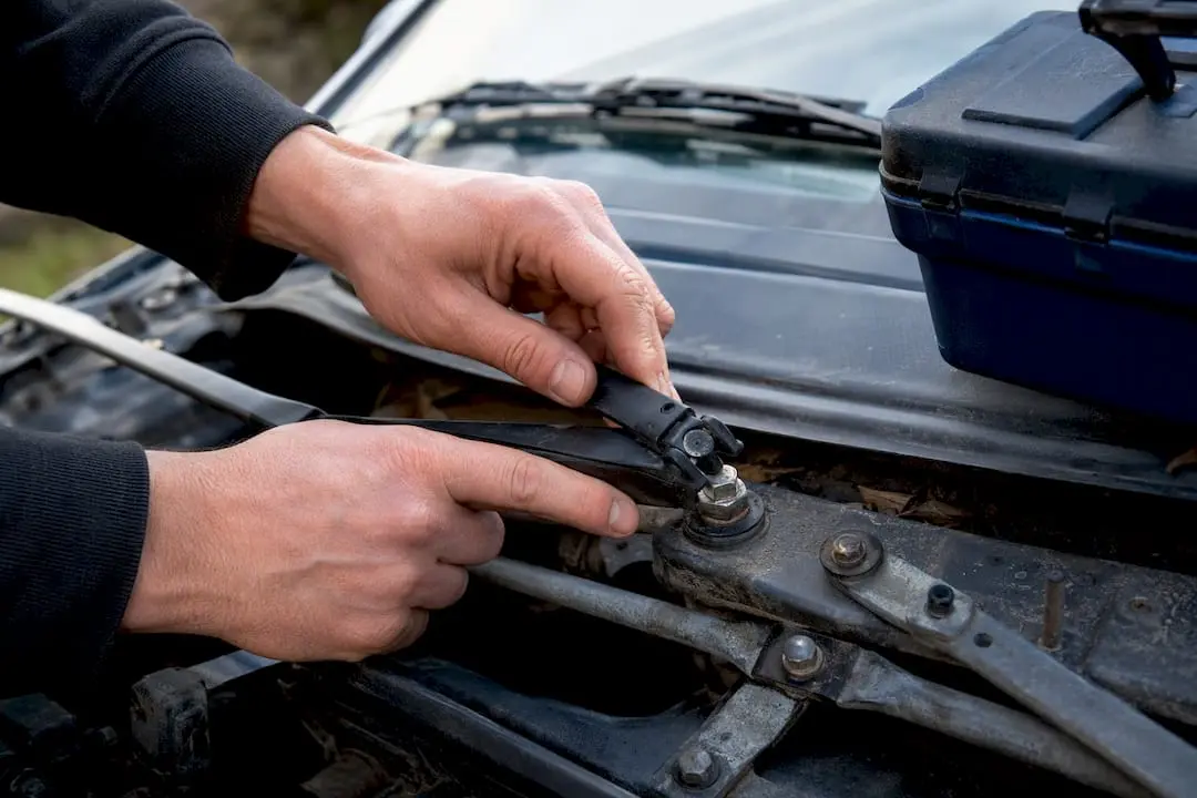 Hands inspecting wiper arm mechanical linkage