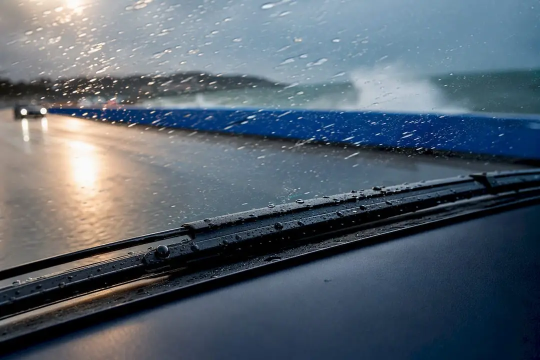 Wiper blade pressed against rain-covered windscreen