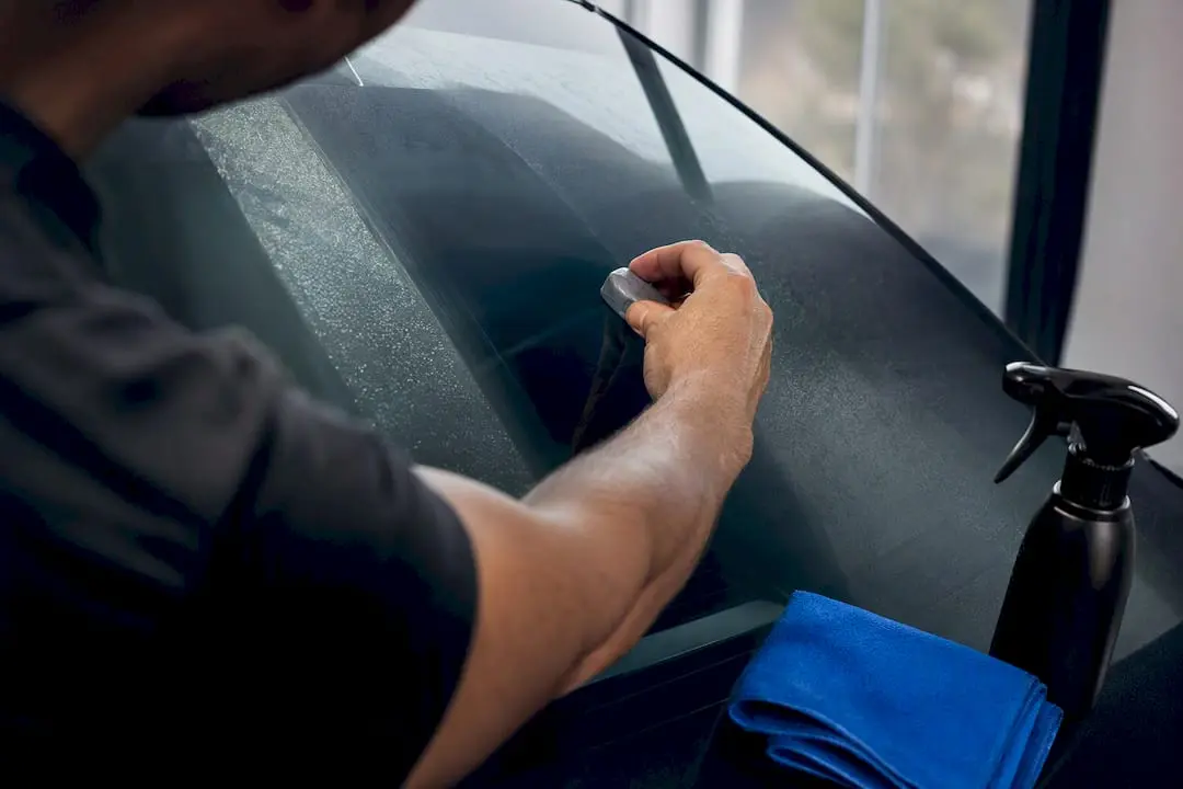 Technician treating windshield with clay bar