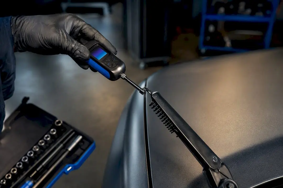Technician testing wiper arm spring tension