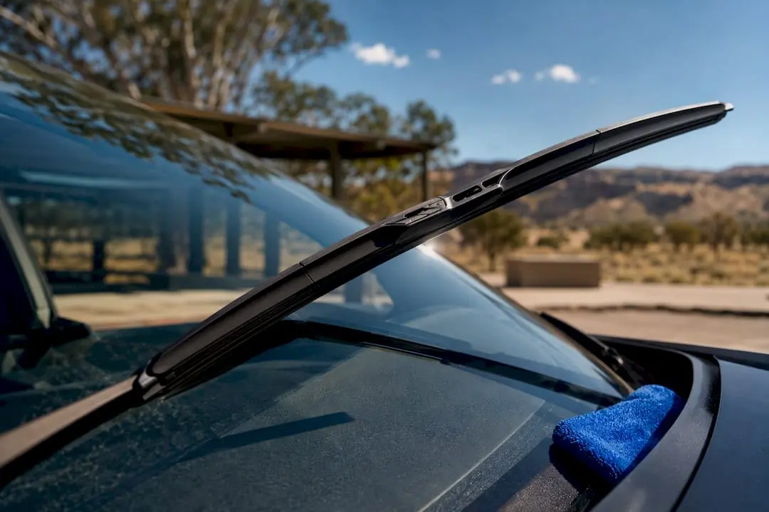 Wiper blade sweeping across sunlit windscreen